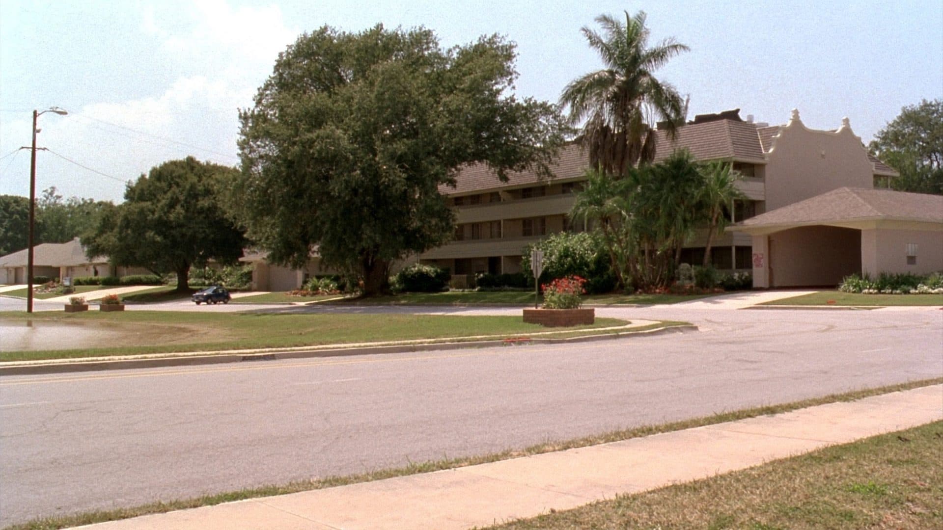 Inner suburban street in Altamonte Springs, Florida, with 1970s stucco condominium buildings, mid century ranch homes, mature oaks and a stormwater retention pond.