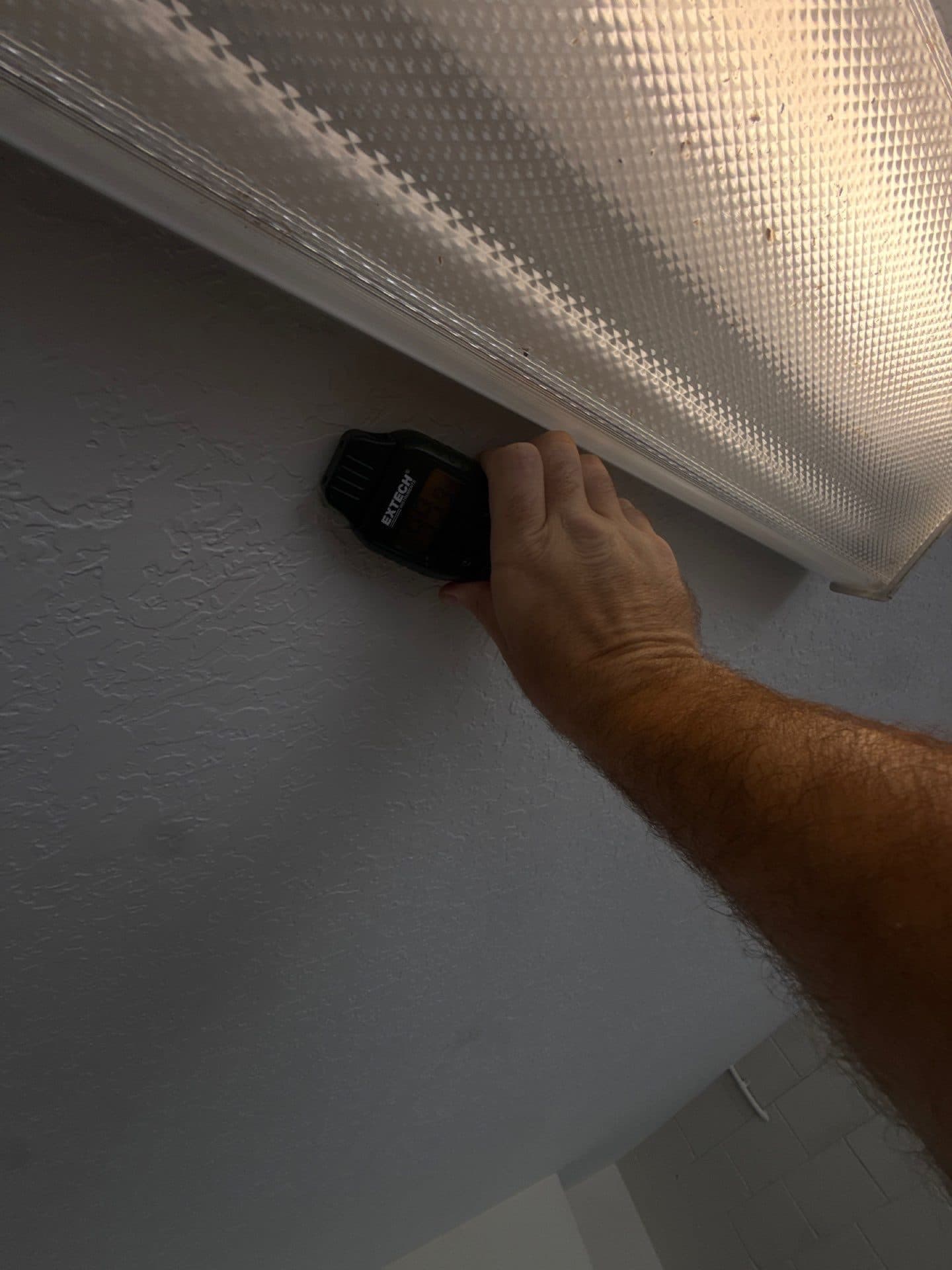 A Ready 2 Inspect crew member taking a moisture reading at a ceiling