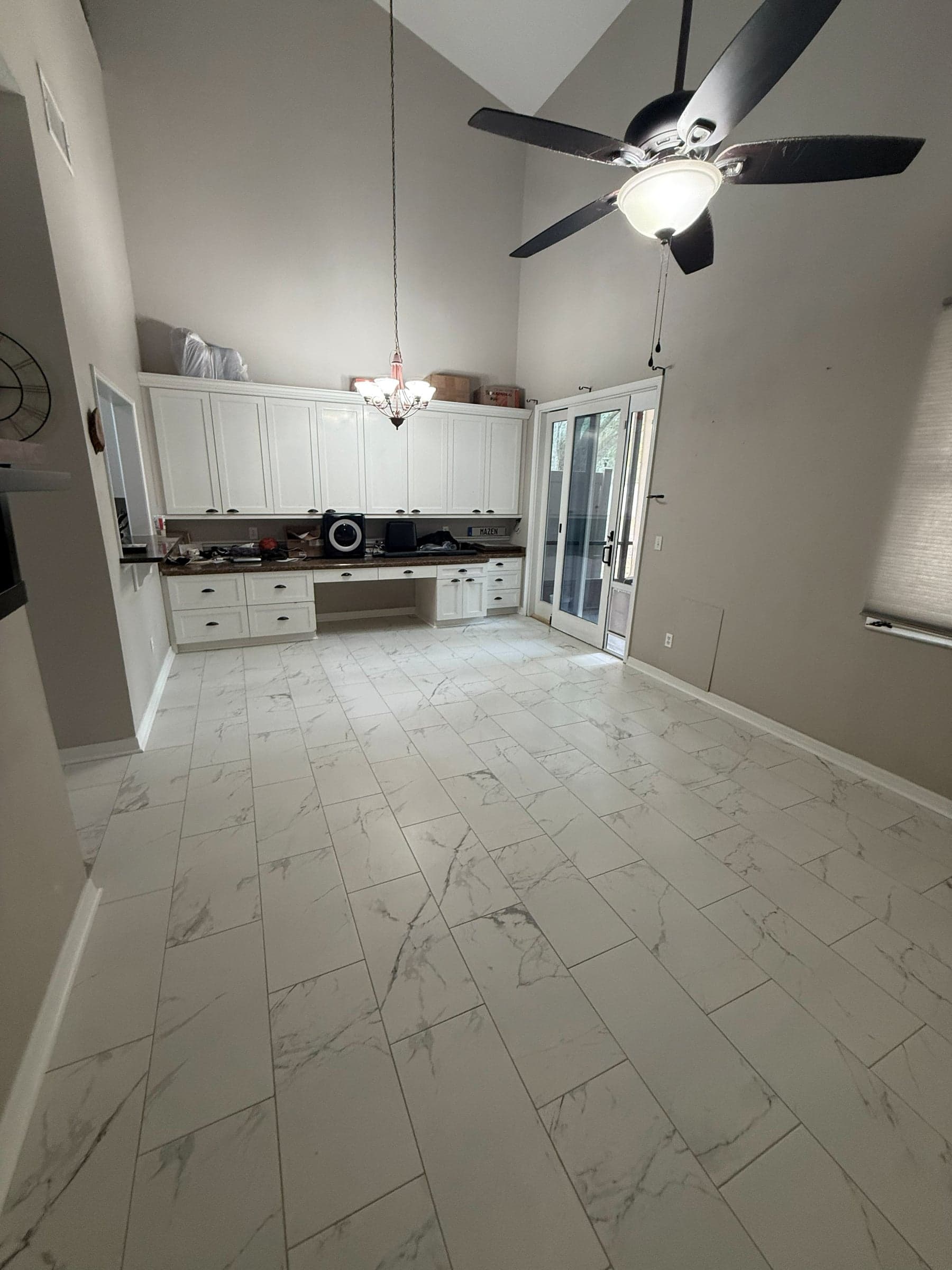 A vaulted great room finished after restoration, with new marble effect tile laid throughout and white cabinetry along the far wall